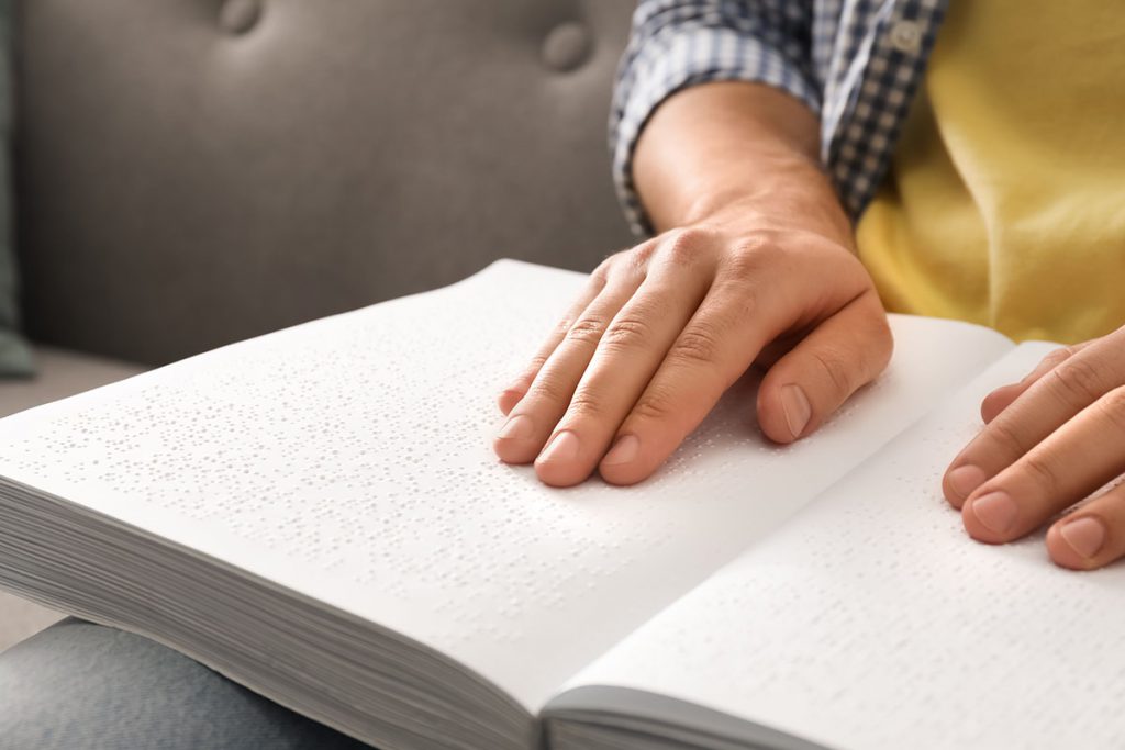 Close up of 2 Hands Reading Braille on a book