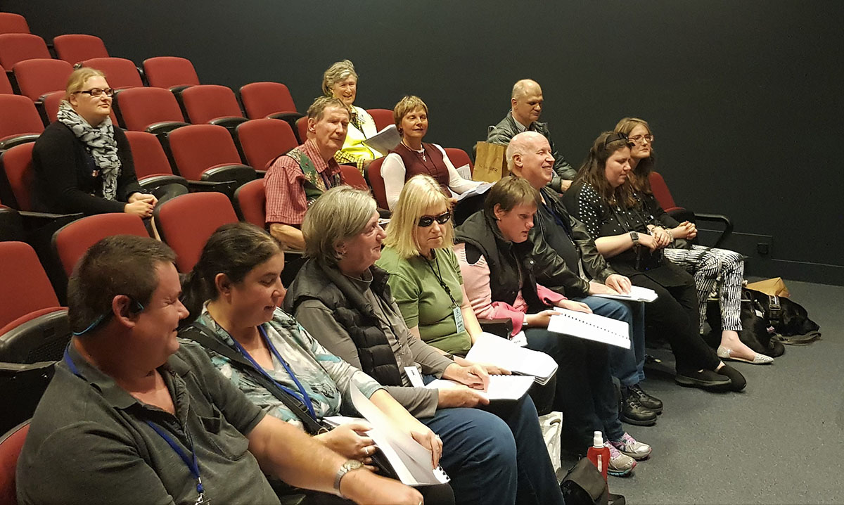 Group of people seated in an auditorium practicing a choir song