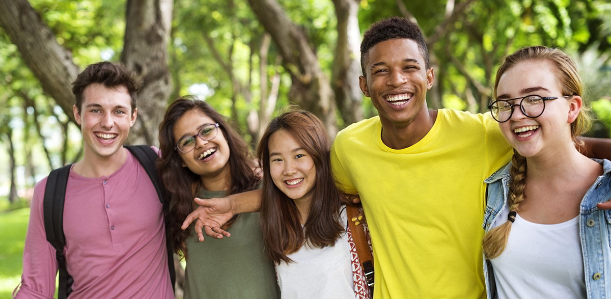 Diverse Group of Young Adults with Arms around Each Other Smiling