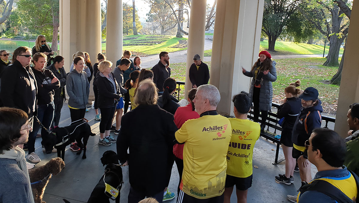 A group of all ages gathers in a park wearing exercise attire