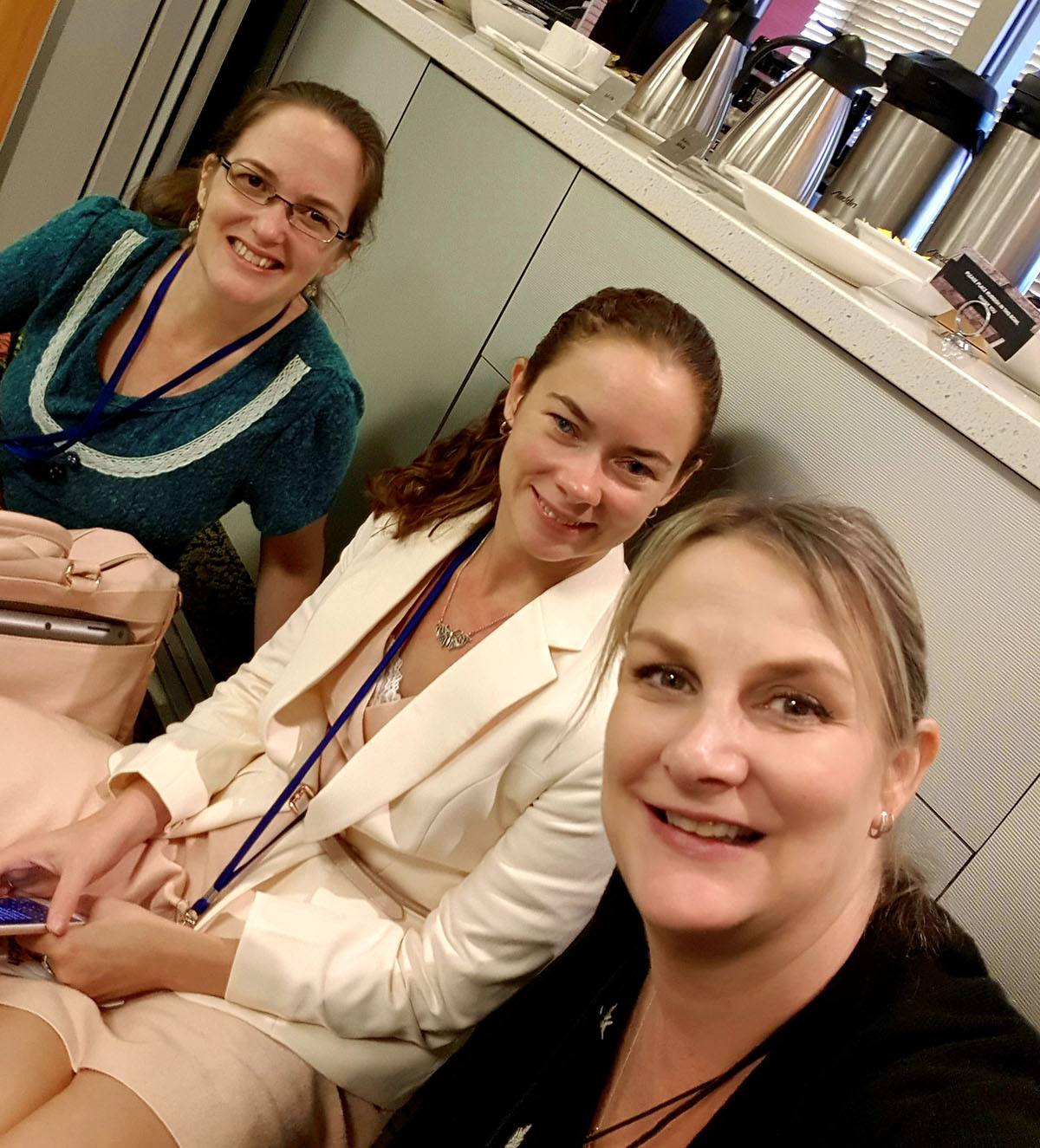 Angled view of three young women smiling at a conference